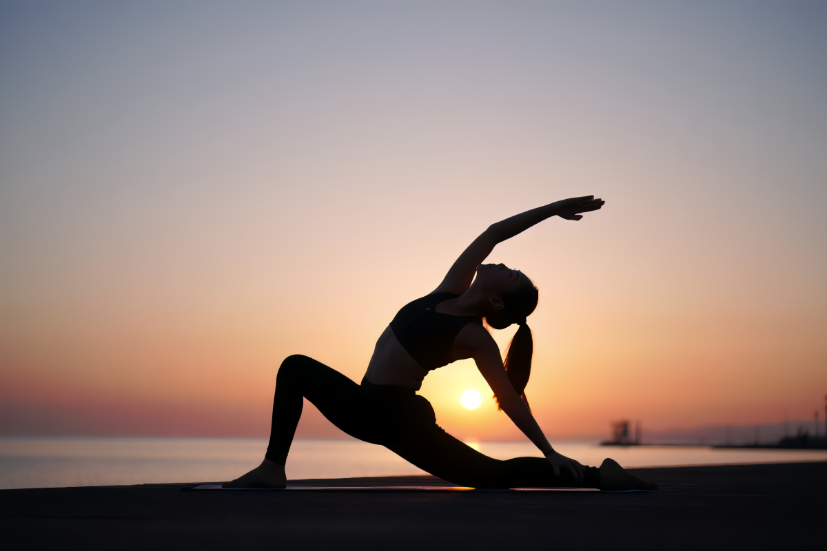 A silhouetted female figure performs an advanced yoga pose