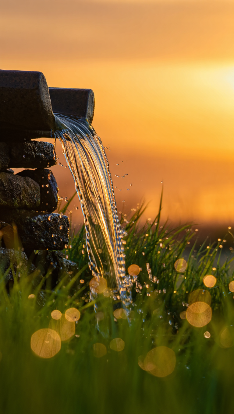 A close-up photography of a stone waterfall at sunset