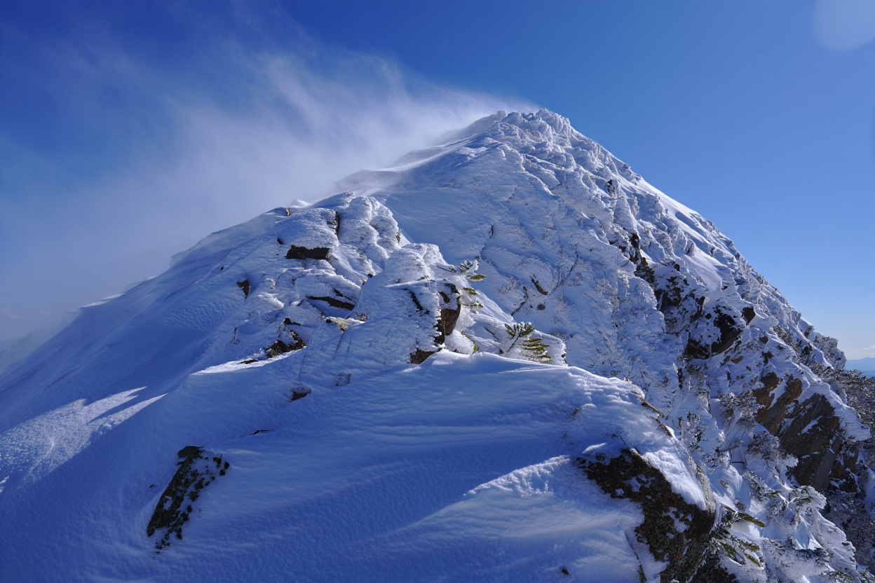 A snow-covered mountain peak rises against a clear blue sky