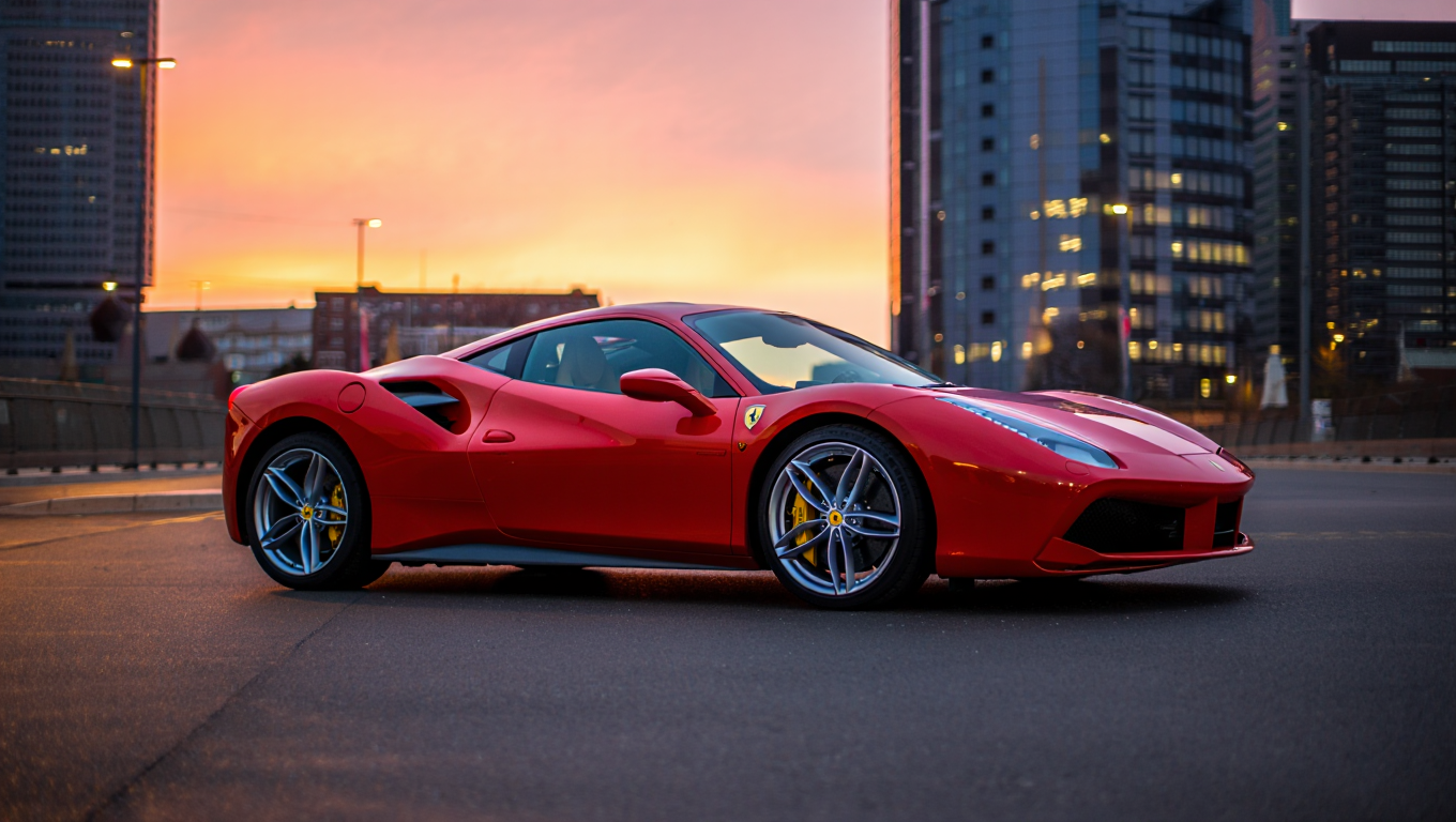 Photography of a red Ferrari 488 GTB parked on a dark gray asphalt city street at dusk